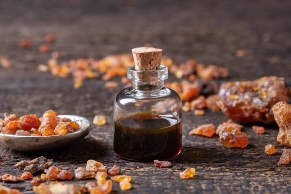 Uma garrafa de óleo essencial de mirra com resina mirra em uma mesa — Fotografia de Stock