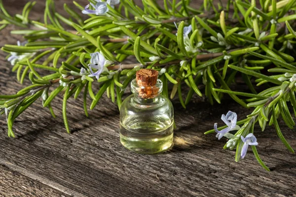 Uma garrafa de óleo essencial de alecrim com galhos de alecrim florescendo — Fotografia de Stock