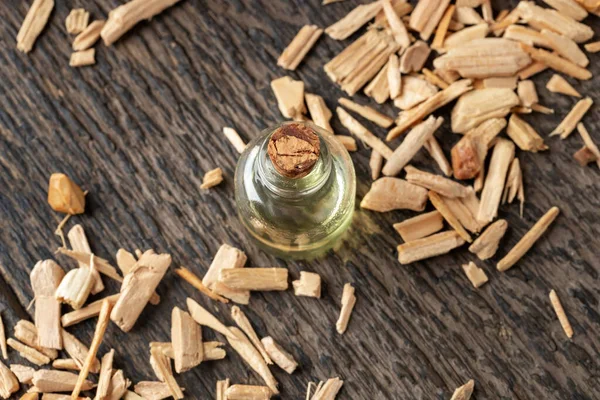 A bottle of cedar essential oil with pieces of cedar wood — Stock Photo, Image