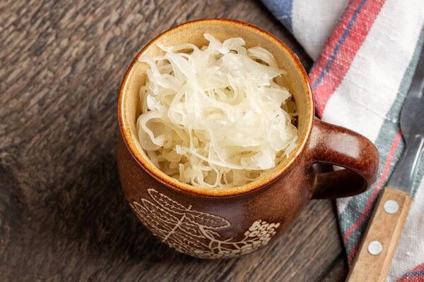 Fermented cabbage in a brown pot on a table