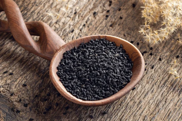 Семена черного тмина на ложке на столе — стоковое фото