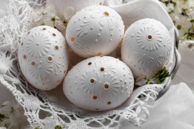 Beyaz paskalya yumurtalarının ayrıntıları balmumuyla süslenmiş, delinmiş deliklerle süslenmiş.
