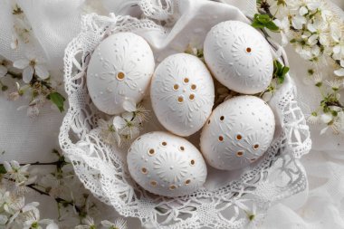 Beyaz Paskalya yumurtaları balmumu ve delinmiş deliklerle süslenmiş.