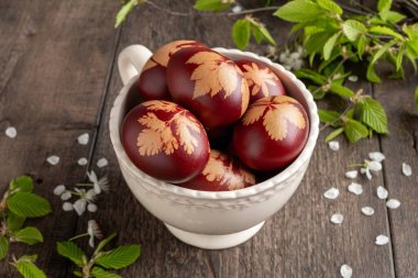 Paskalya yumurtaları soğan kabuklarıyla boyanmış ve bir kasede yaprak deseni var.