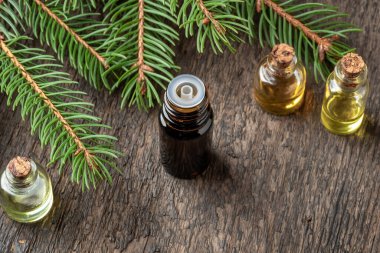 İçinde ladin dalları olan koyu renkli bir yağ şişesi.