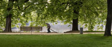 PRAG, CZECH Cumhuriyet - 22 Mayıs 2020: Strelecky Adası 'ndaki patikaları süpürge ile temizleyen yaşlı adam