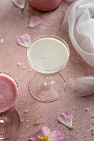 A glass of goats milk kefir on a pink background