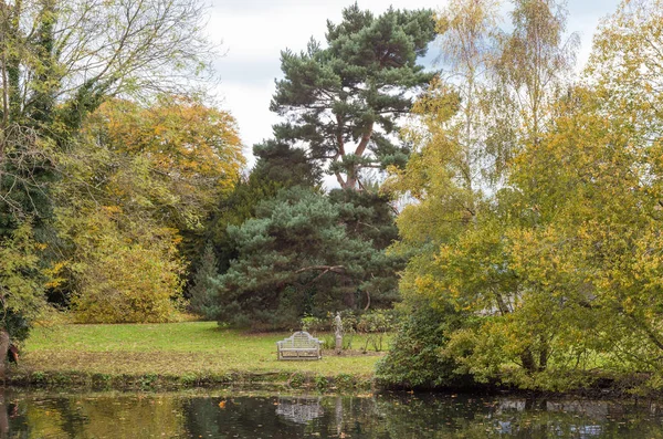 Banco junto al lago en un jardín otoñal — Foto de Stock