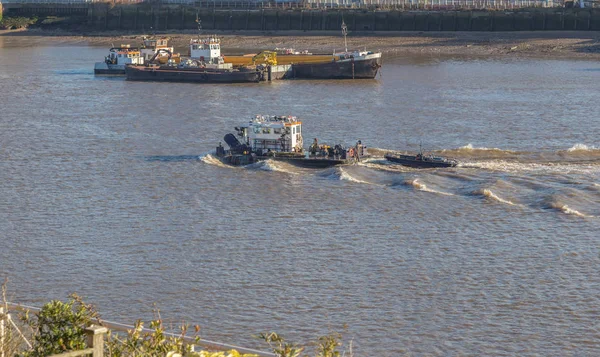 Barge, working vessel on the River Thames, travelling fast, with