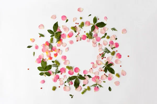 Цветочная круглая рамка с лепестками роз и зелеными листьями на белом — стоковое фото