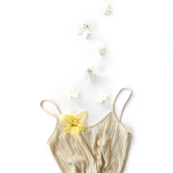 Vestido dorado y flores en movimiento sobre fondo blanco. Puesta plana —  Fotos de Stock