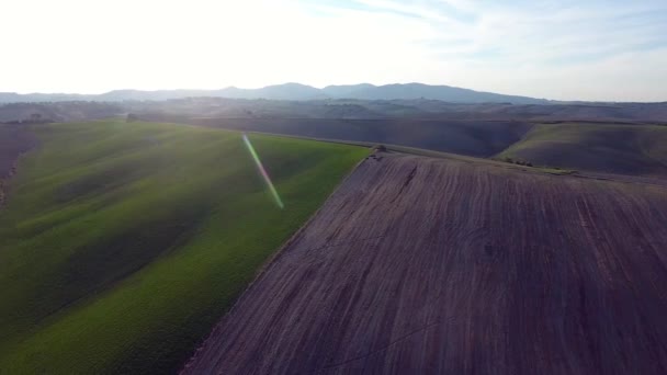 Aerial shot, gorgeous tucany hills landscape with sun flare, flying above the fields, tuscany flyover — Stockvideo