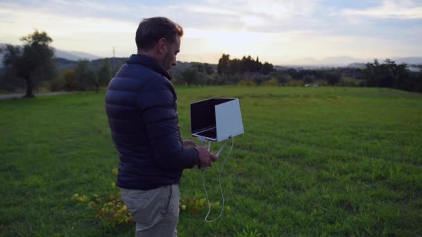 Hombre, mirando su tableta y sonriendo mientras pilota el dron en los campos, enfoque selectivo — Vídeos de Stock