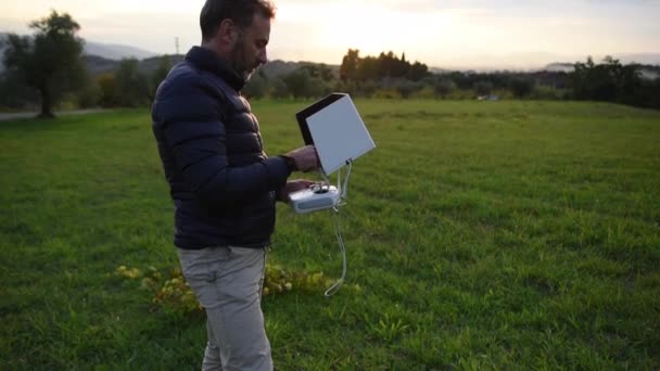 Muž, sledoval jeho tabletu a usmíval se při pilotování dron v polích, Selektivní ostření — Stock video