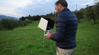  Onun tableti izliyor ve sunset bulvarında dron seçici odak alanları, pilotluk ederken gülümseyen aşağı ceket giymiş sakallı bir adam