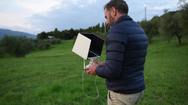 El hombre barbudo vestido con la chaqueta baja hace que su dron despegue en la carretera del campo — Vídeos de Stock