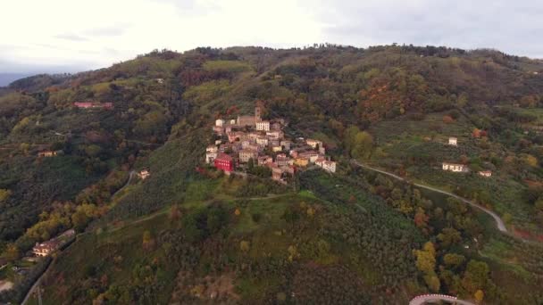 Légi lövés, gyönyörű kis falu a domb felüljáró, a közepén az őszi színek — Stock videók