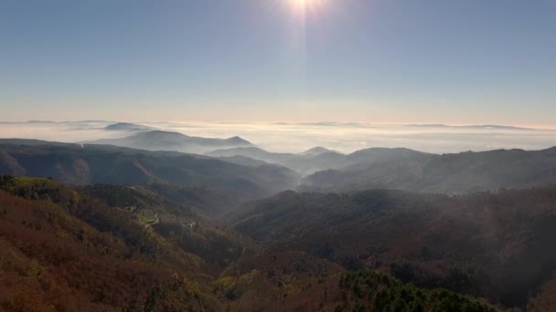 Воздушный кадр, великолепные холмы в утреннем тумане, солнце высоко в небе и красивые осенние цвета — стоковое видео