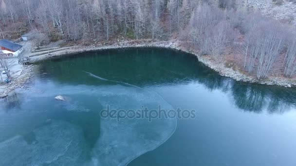 Letecký snímek, krásné zamrzlé jezero v tmavě modré barvy, obklopen mrazem, ležící uprostřed hor — Stock video