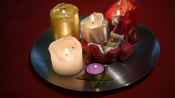 Vidéo de belles bougies de Noël allumées et d'une petite statuette de Père Noël endormie — Video