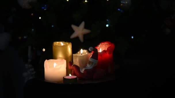 Video de hermosas velas de Navidad encendidas y una pequeña estatuilla de Papá Noel durmiendo, frente al árbol de Navidad — Vídeos de Stock