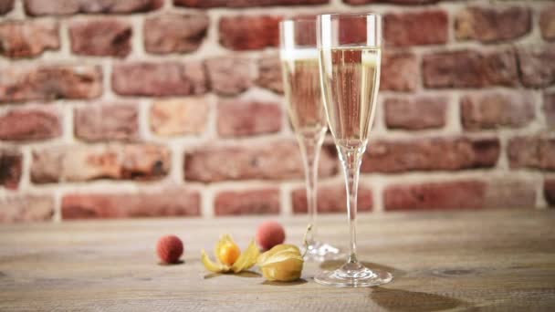 Video of two flutes of champagne on the wooden table with the brick background, selective focus — Stock Video