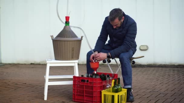 Uomo con la barba che riempie alcune bottiglie di vino con vino bianco, focus selettivo — Video Stock