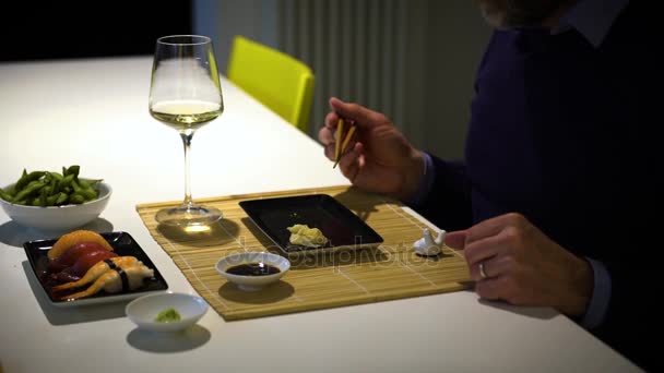 Hombre con barba comiendo sushi y bebiendo vino blanco durante la cena — Vídeos de Stock