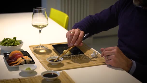 Hombre con barba comiendo sushi y bebiendo vino blanco durante la cena — Vídeos de Stock