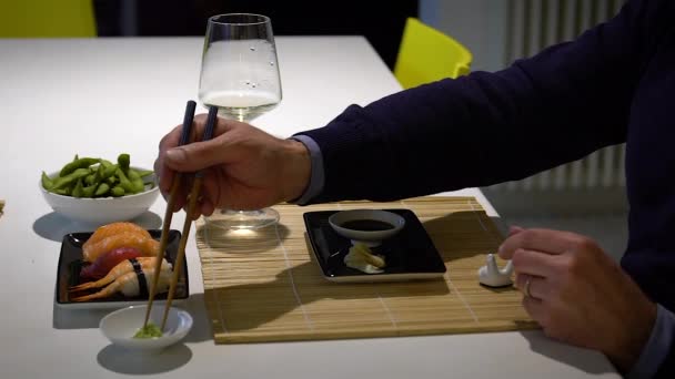 Vídeo en cámara lenta del hombre con barba comiendo sushi y bebiendo vino blanco durante la cena — Vídeos de Stock