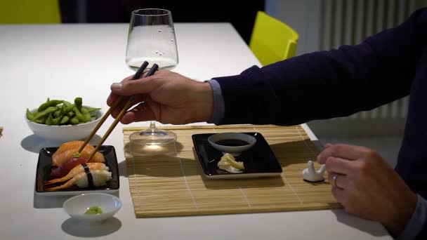 Vídeo en cámara lenta del hombre con barba comiendo sushi y bebiendo vino blanco durante la cena — Vídeos de Stock