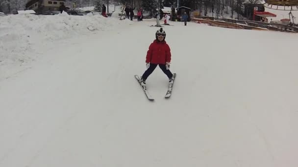 En liten flicka med gopro på hennes hjälm som tar hennes första ski lektion, Hd — Stockvideo