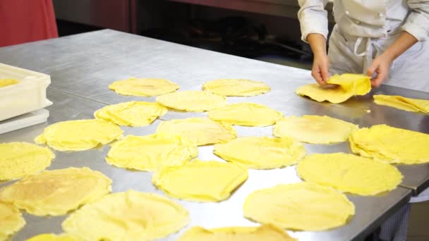 Una cocinera en la cocina del restaurante de catering poniendo algunos panqueques o crepes antes de rellenar con el relleno, 4K — Vídeo de stock