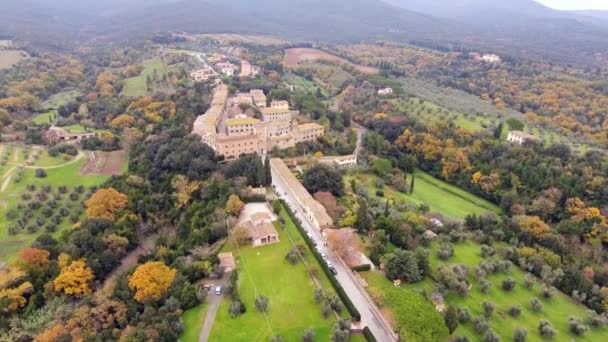Luchtfoto schot, een kleine oude stadje in het midden van de rurale landschap met ontgonnen veld en een heleboel olijfbomen in Toscane, Italië, schoot met drone, 4 k — Stockvideo