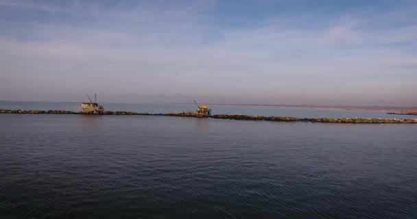 Plano aéreo de algunas casas de pescadores con enormes redes fuera situado en medio del mar, en Toscana, Italia, filmado con dron — Vídeos de Stock