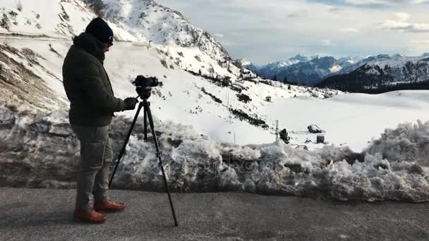 Um fotógrafo em altas montanhas de Alpes nevados atirando em uma paisagem com um vento muito forte, na Itália . — Vídeo de Stock