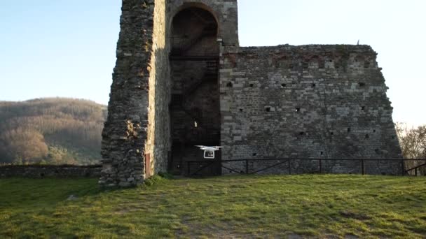 Белый квадрокоптер взлетает возле средневековых стен, в Тоскане, Италия, 4К — стоковое видео