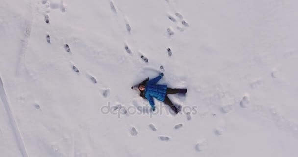 Luchtfoto van een klein meisje het maken van een engel van de sneeuw in de sneeuw, 4k — Stockvideo