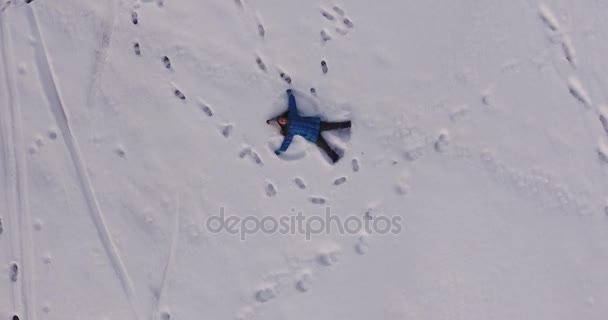 Antenn skott av en liten flicka att göra en snöängel i snön, 4k — Stockvideo