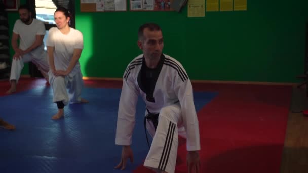 Sesión de entrenamiento de taekwondo para adultos en el gimnasio, estiramiento, enfoque selectivo, 4K — Vídeo de stock