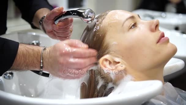 Egy fiatal gyönyörű nő egyre fodrásznál, 4k mossa a haját — Stock videók