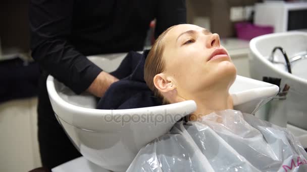 Una giovane bella donna che si lava i capelli dai parrucchieri, 4K — Video Stock