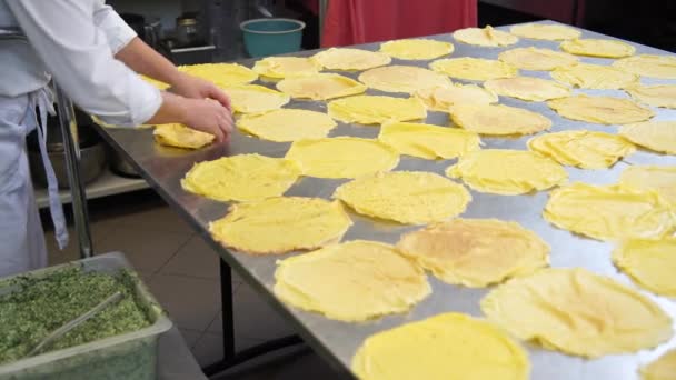 En kvinnlig kock i catering restaurangköket att sätta ner några pannkakor eller crepes innan du fyller dem med fyllningen, 4k — Stockvideo