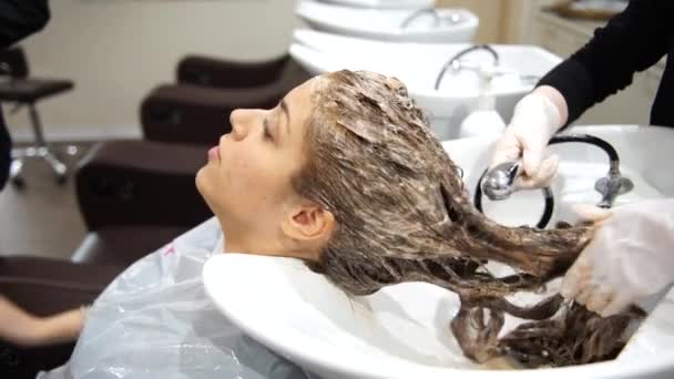 Una joven hermosa mujer que se lava el pelo en los peluqueros, 4K — Vídeos de Stock