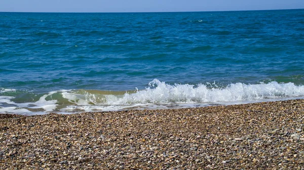 Bir çakıl plaj ve gökyüzü arka planda Deniz sörfü