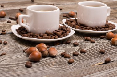 iki küçük beyaz fincan kahve kakao çekirdekleri, çikolata ve fındık ahşap arka plan üzerinde dilimleri ile