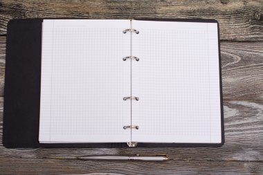 Ahşap arka plan üzerinde not defteri ve metal kalem