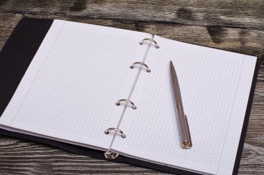 Ahşap arka plan üzerinde not defteri ve metal kalem