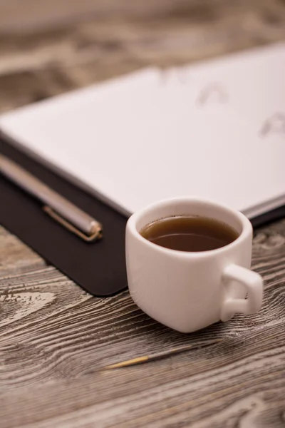 नोटपैड, धातु पेन और लकड़ी की पृष्ठभूमि पर छोटे सफेद कप कॉफी — स्टॉक फ़ोटो, इमेज
