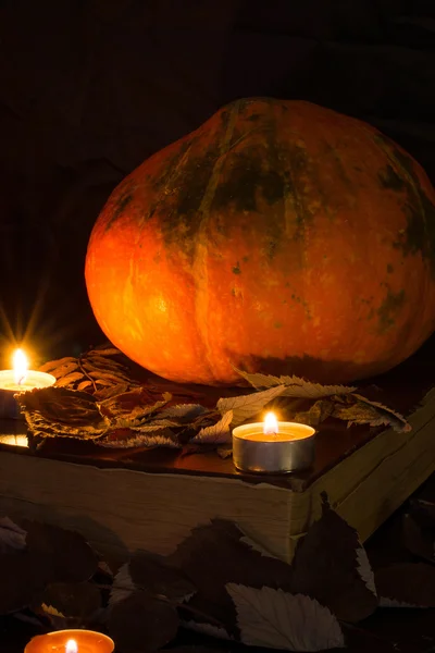 Zucca, vecchio libro, candele e foglie secche gialle. Piano piano. Composizione di Halloween — Foto Stock
